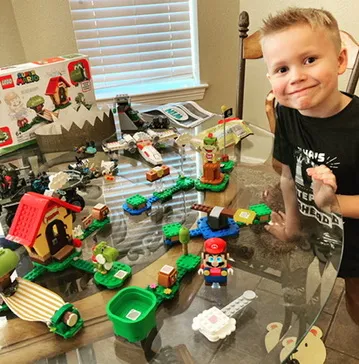 CJ smiling beside a big brick build on a table