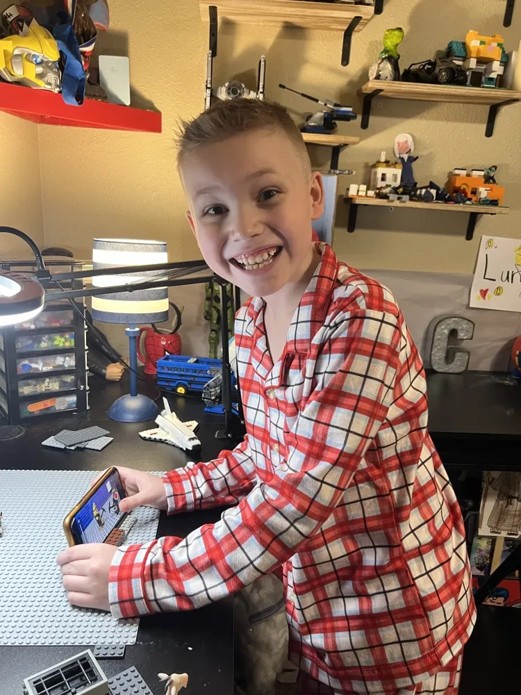 CJ grinning at his desk with his phone and a baseplate